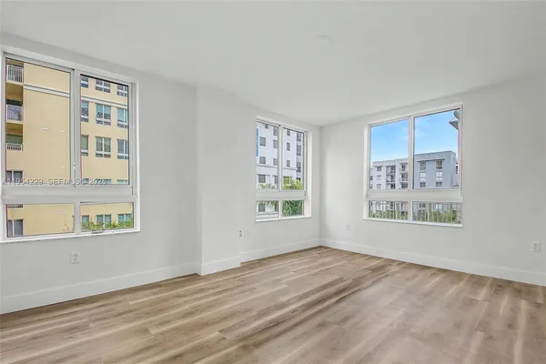 a view of an empty room with a window and wooden floor