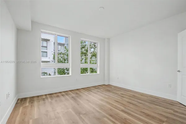 a view of an empty room with wooden floor and a window