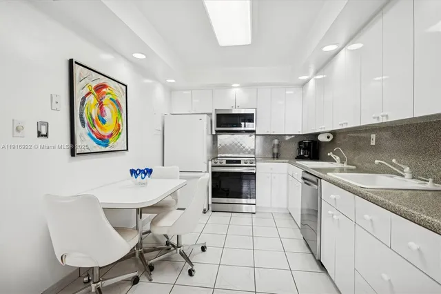 a kitchen with stainless steel appliances a sink a stove a refrigerator cabinets and dining table