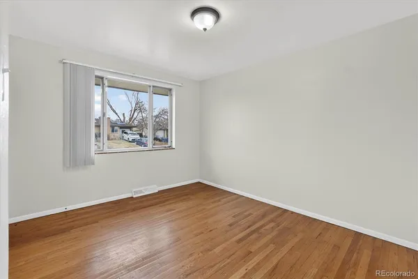 an empty room with wooden floor and window