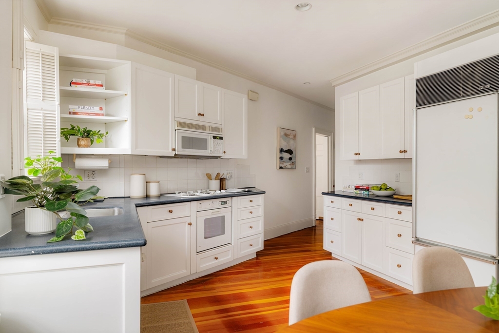 984 Memorial Drive, Unit 984503 Cambridge, MA 02138 - Photo 16 of 30 a kitchen with stainless steel appliances granite countertop a refrigerator a stove a sink and white cabinets with wooden floor