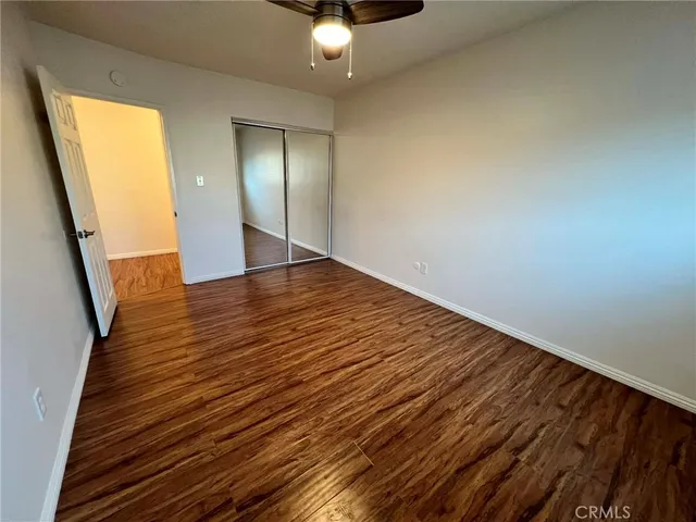 a view of an empty room with wooden floor and a chandelier