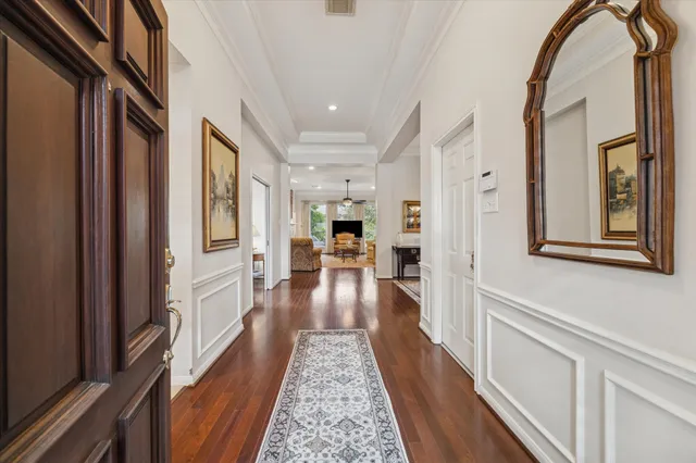 a hallway with wooden floor chandelier and living room