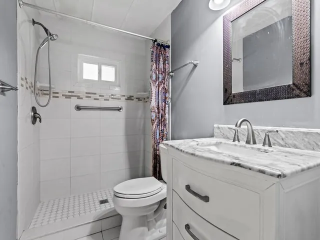a bathroom with a granite countertop sink mirror vanity and toilet