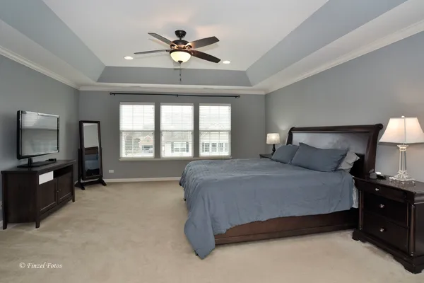 a spacious bedroom with a bed a window and dresser