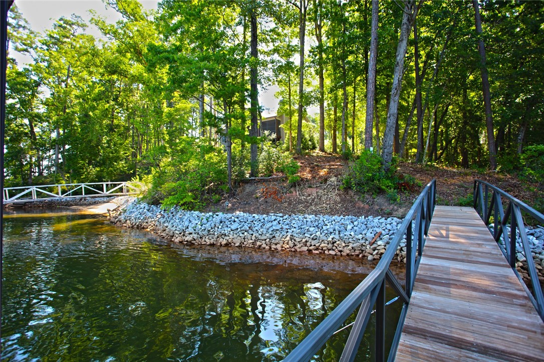 1359 Hbr Rdg Road Seneca, SC 29672 - Photo 29 of 39 A private boat slip and sturdy dock extend over tranquil waters, framed by verdant trees and a rock-lined shore.