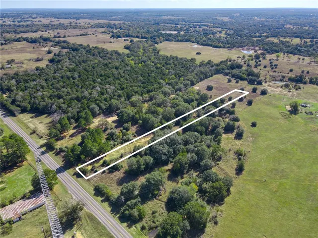 an aerial view of residential houses with outdoor space and trees