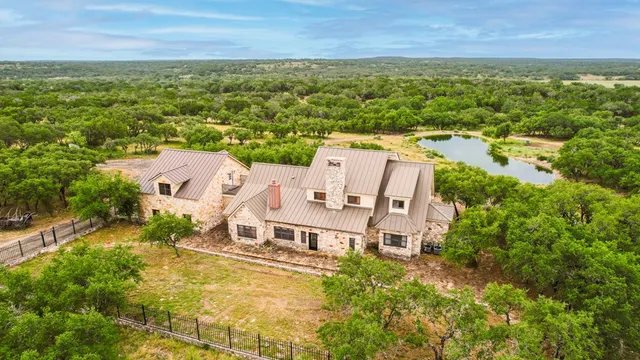 an aerial view of residential house with outdoor space and trees all around