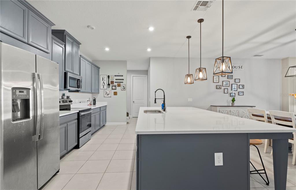 2731 Rialto Court Kissimmee, FL 34746 - Photo 13 of 49 a large kitchen with stainless steel appliances kitchen island granite countertop a refrigerator a sink a stove and oven