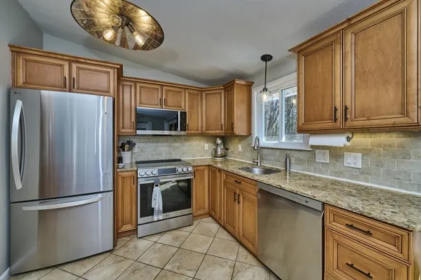 a kitchen with stainless steel appliances granite countertop a refrigerator stove top oven and sink