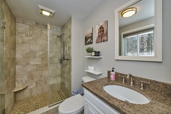 a bathroom with a granite countertop sink toilet a shower and a mirror