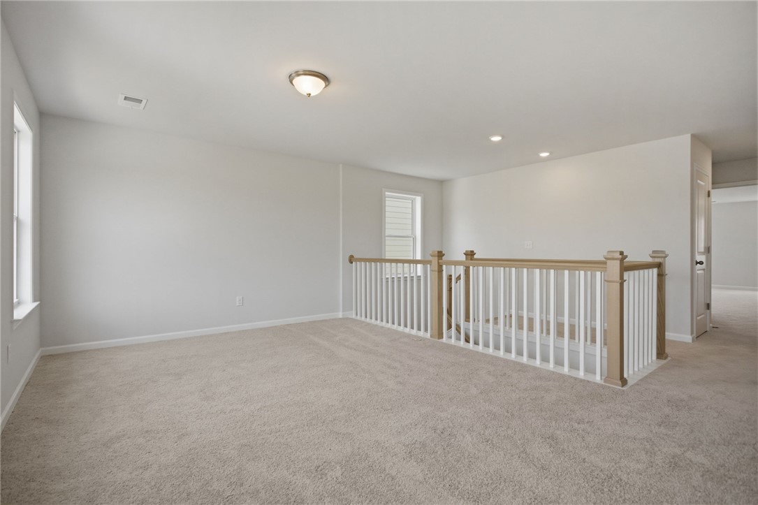 557 Hydrangea Street, Unit LOT 46 Seneca, SC 29678 - Photo 13 of 37 A spacious, naturally illuminated loft area boasts soft carpeting and a modern banister overlooking the lower level.