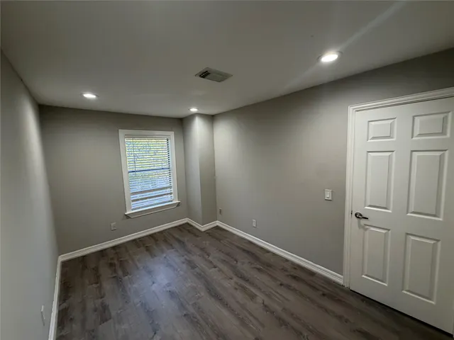 an empty room with wooden floor and a window