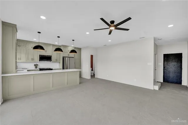 a large white kitchen with stainless steel appliances kitchen island a refrigerator sink and white cabinets