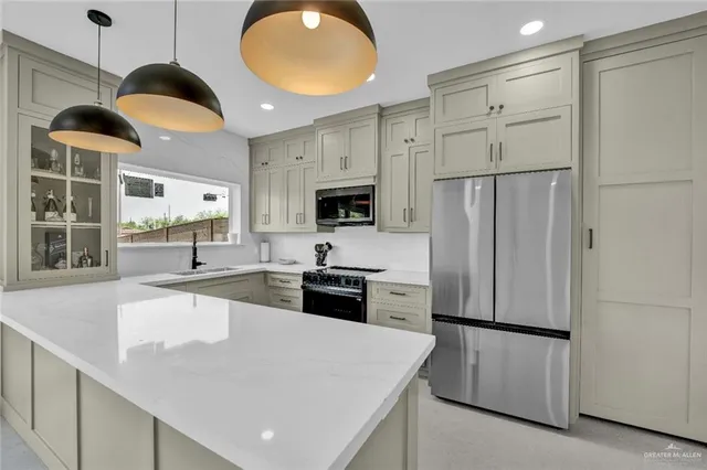 a kitchen with stainless steel appliances a refrigerator a stove a sink and a large window