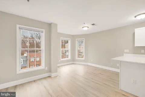 a view of an empty room with a window and wooden floor