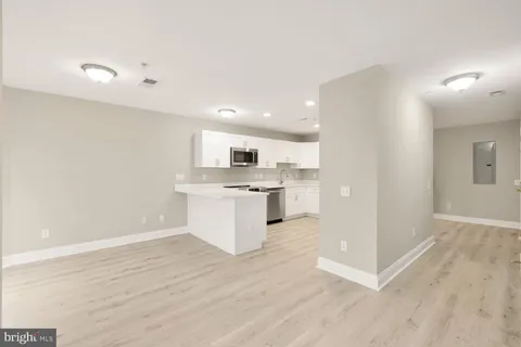 a view of kitchen with granite countertop refrigerator oven sink and white cabinets