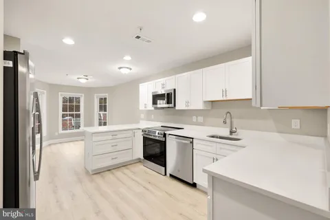 a kitchen with stainless steel appliances granite countertop a sink and dishwasher a stove top oven with white cabinets