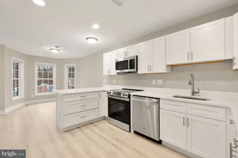 a kitchen with granite countertop white cabinets and stainless steel appliances