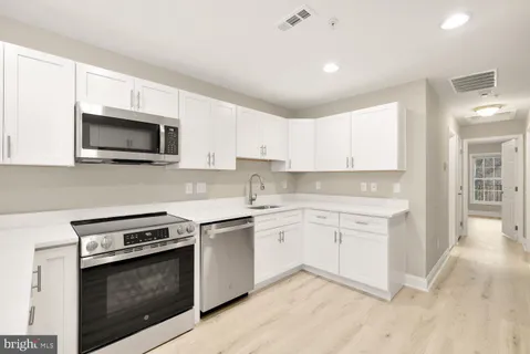 a kitchen with granite countertop white cabinets sink and stainless steel appliances