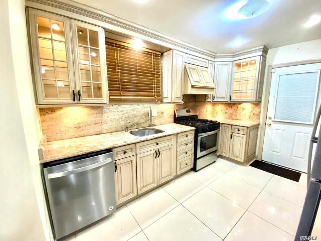 a kitchen with granite countertop a stove a sink and a refrigerator
