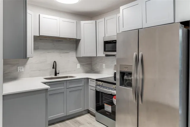 a kitchen with stainless steel appliances a refrigerator sink and white cabinets