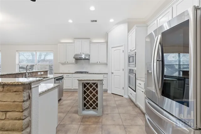 a kitchen with stainless steel appliances granite countertop a refrigerator a stove and a sink