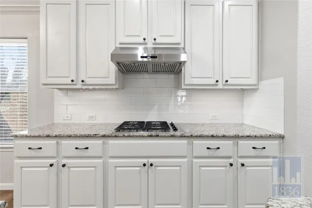 a kitchen with granite countertop white cabinets and a stove