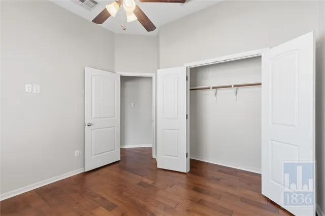 an empty room with wooden floor closet and windows