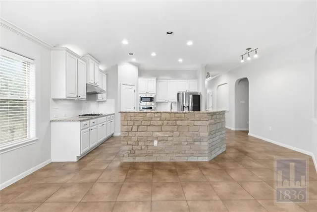 a living room with stainless steel appliances kitchen island granite countertop lots of white cabinets