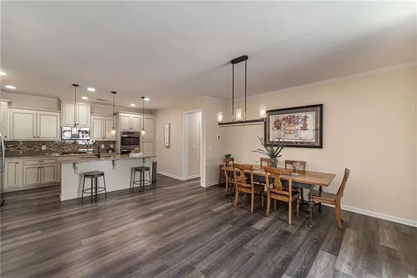 a kitchen with stainless steel appliances granite countertop a stove top oven a sink dishwasher a dining table and chairs with wooden floor