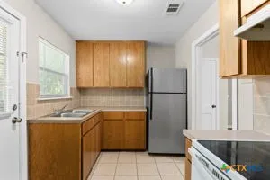 an empty room with chandelier fan and windows