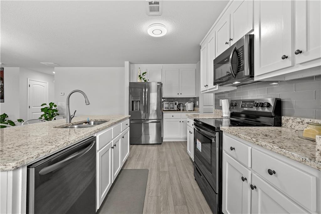 68 Suwannee Way Jefferson, GA 30549 - Photo 16 of 28 a kitchen with stainless steel appliances granite countertop a kitchen island a stove a sink and a microwave