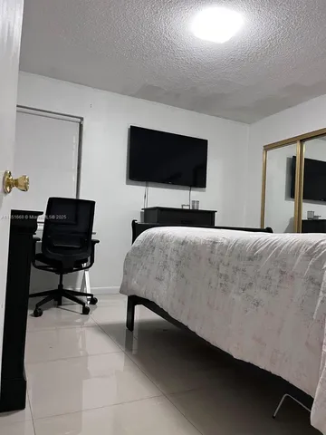 a bedroom with a bed a television and a couch