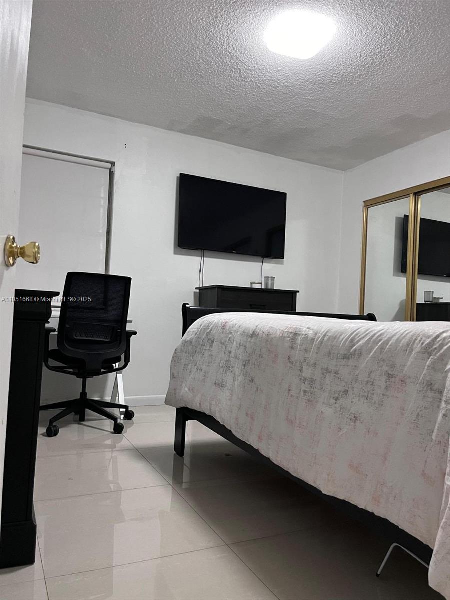 2496 Southwest 17th Avenue, Unit 5301 Miami, FL 33145 - Photo 17 of 19 a bedroom with a bed a television and a couch