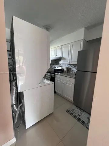 a kitchen with a refrigerator a stove top oven and cabinets