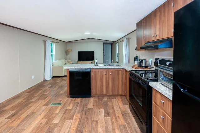 a kitchen with a stove top oven a sink dishwasher and a refrigerator with wooden floor