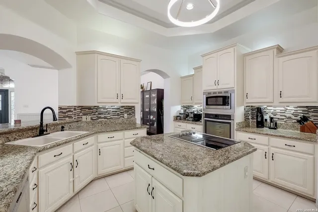 a kitchen with granite countertop a sink stainless steel appliances and white cabinets