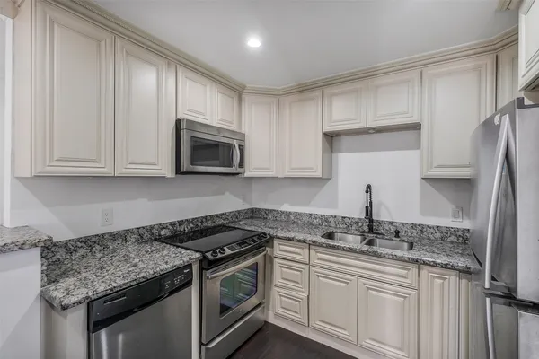 a kitchen with granite countertop a sink stove and microwave