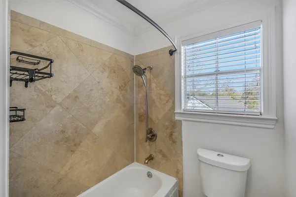 a bathroom with a shower a toilet and a window