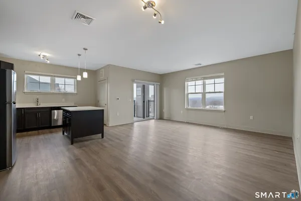 a view of an empty room with window and wooden floor