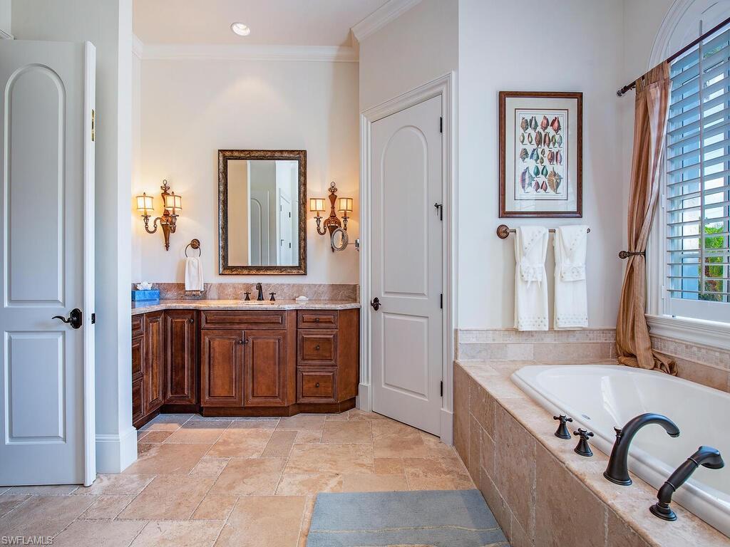 155 20th Avenue South Naples, FL 34102 - Photo 18 of 30 Bathroom featuring vanity, a garden tub, crown molding, and stone tile flooring