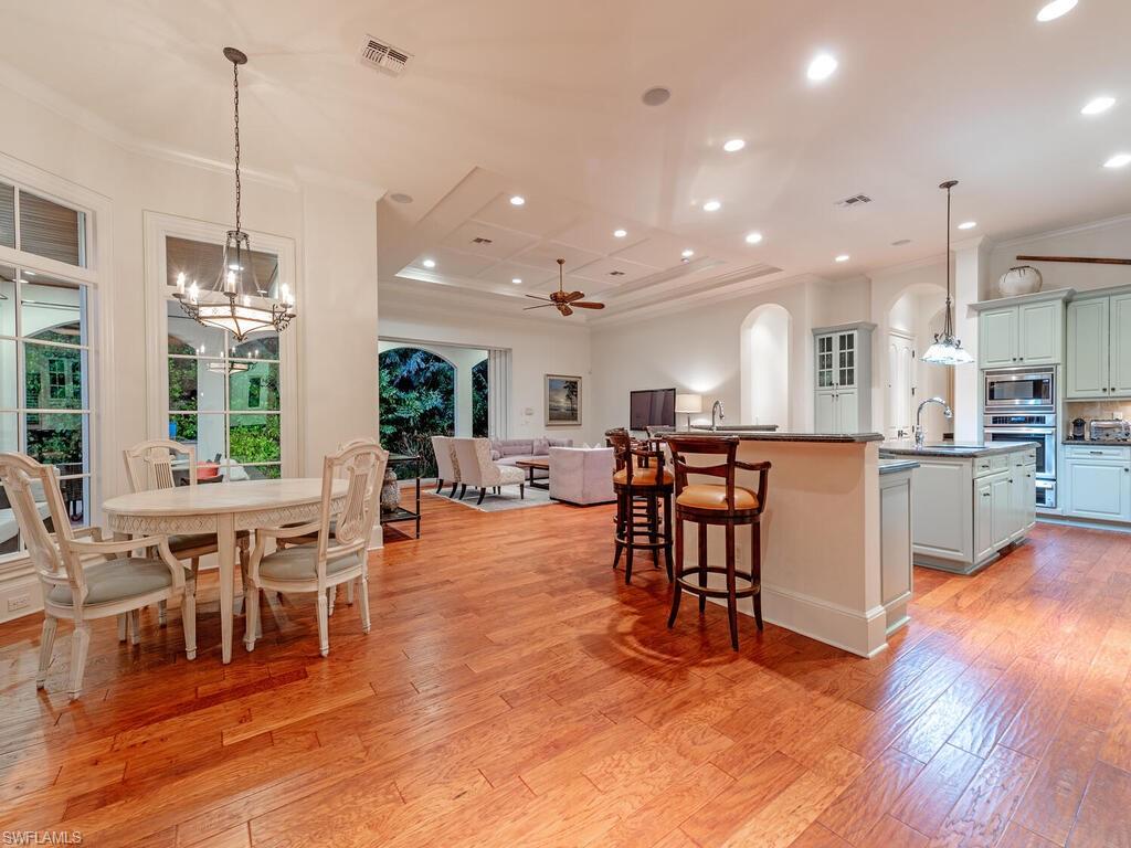 155 20th Avenue South Naples, FL 34102 - Photo 24 of 30 Kitchen featuring pendant lighting, a ceiling fan, crown molding, a breakfast bar, and light wood-type flooring