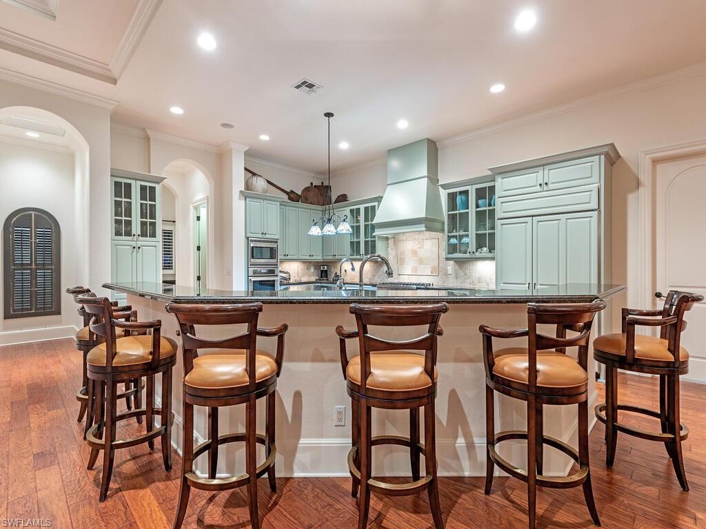155 20th Avenue South Naples, FL 34102 - Photo 25 of 30 Kitchen with glass insert cabinets, decorative backsplash, ornamental molding, dark wood-style flooring, and recessed lighting