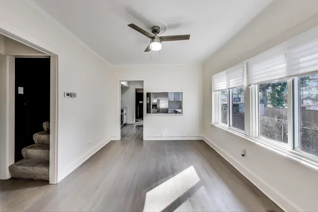 a view of an empty room with a window and wooden floor