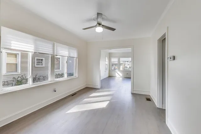a view of empty room with wooden floor and fan