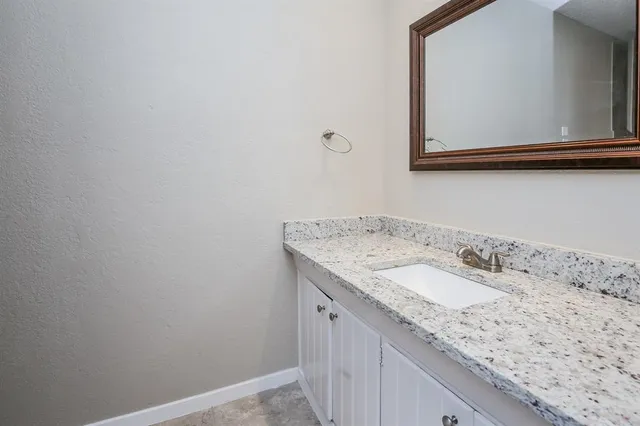 a bathroom with a granite countertop sink and a mirror