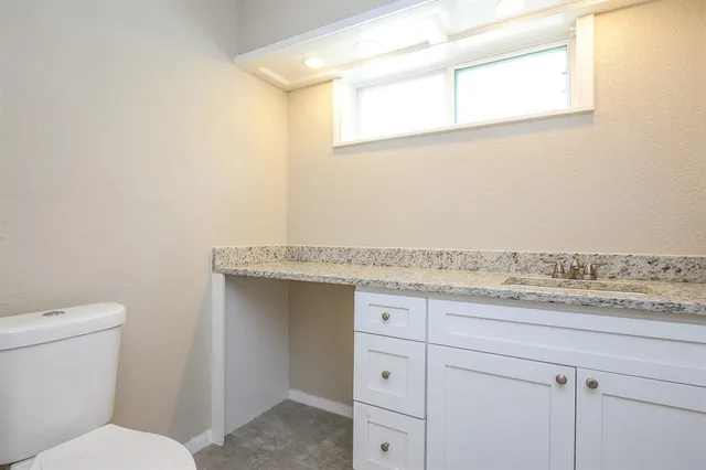 a bathroom with a granite countertop sink and a toilet