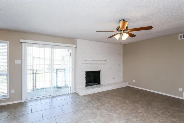 a view of an empty room with a fireplace and a window