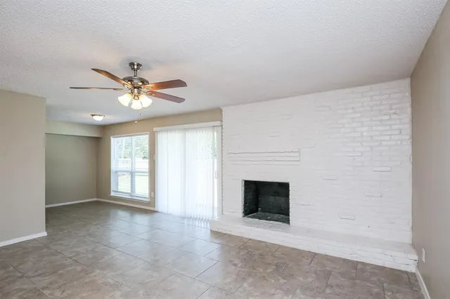 an empty room with windows and fireplace